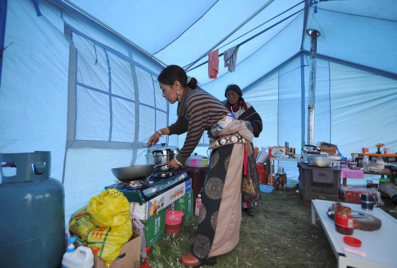 四川省阿坝藏族羌族自治州若尔盖县的一名藏族妇女在帐篷内做饭(2009